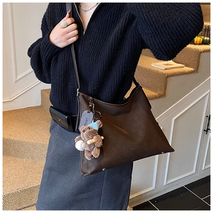 Detail of vintage brown embossed tote bag with cute bear charm and baseball accessory
