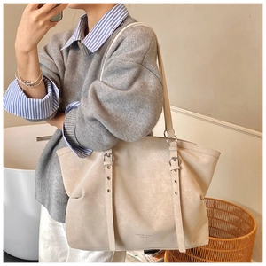Close-up of beige tote bag with vintage leather texture and silver eyelet shoulder strap