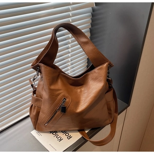 Close-up of brown textured leather tote bag showing grainy finish and zipper detail