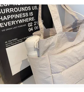 Detail view of the cream tote bag side pocket holding a water bottle for storage