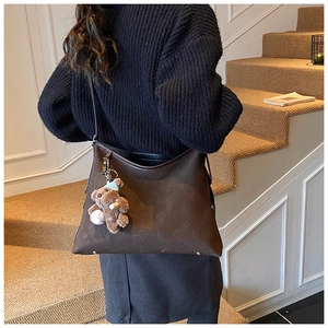 Deep brown leather tote bag with floral embossing and cute plush bear charm detail