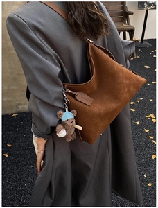 Detail of hobo bag featuring logo embossing and cute brown bear keychain accessory