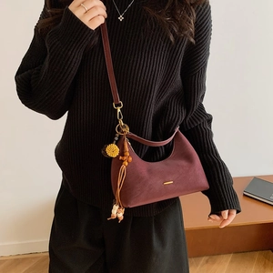 Detail of burgundy leather hobo bag featuring beaded tassels and gold trim on shoulder strap