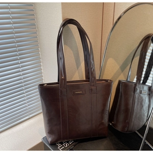 Détail du sac cabas en cuir marron foncé brillant avec fines bretelles et fermeture éclair