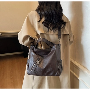 Detail of dark brown leather tote bag with zip pocket and wide adjustable strap