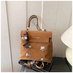 Détail du sac à dos en cuir givré caramel avec poignée tressée et patchs en étoile