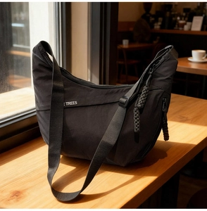 Detail of black crescent canvas bag showing adjustable strap and textured nylon fabric