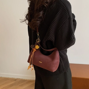 Detailed view of dark red leather hobo bag with gold hardware and wood bead tassel
