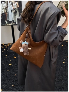 Detail of a brown embossed leather hobo bag with floral pattern and bear charm