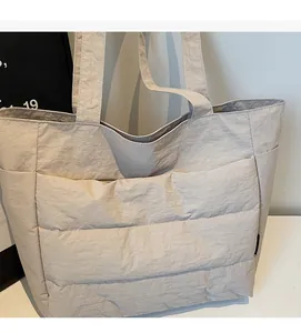 Detail view of beige quilted tote bag showing textured nylon fabric and side pocket