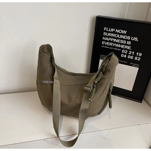 Close-up of army green canvas crescent bag with white logo and adjustable shoulder strap