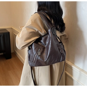 Detail of a dark brown oil-wax leather tote bag with silver zipper and wide strap