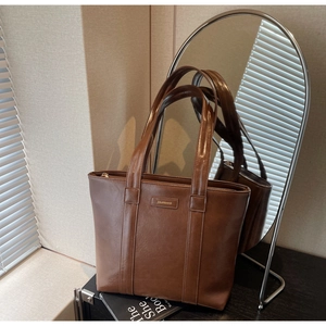 Détail d'un grand sac cabas marron foncé en cuir brillant avec fermeture éclair et anses
