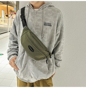 Close-up of green checkered crossbody chest bag featuring a front brand logo and nylon strap