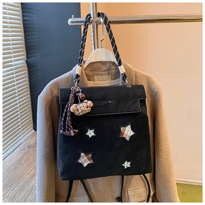 Détail d'un sac à dos noir mat avec des appliques en étoile et un charm d'ours à carreaux