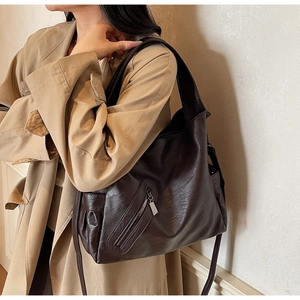 Detail of soft brown PU leather tote bag with wide strap and decorative front zipper