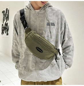 Close-up of army green checkered crossbody chest bag worn by a model in casual style