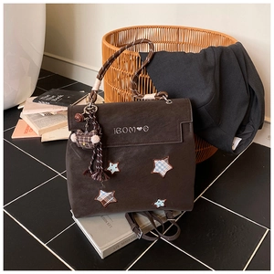 Détail du sac à dos marron mat avec écussons étoiles, broderie et breloque ours