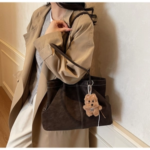 Brown suede tote bag with white contrast stitching and a plush dog pendant detail