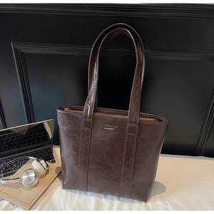Détail du sac cabas vintage en cuir marron avec logo métallique dans un décor de bureau
