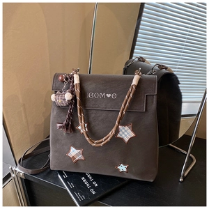 Détail d'un sac à dos gris givré avec broderie étoile et breloque petit ours