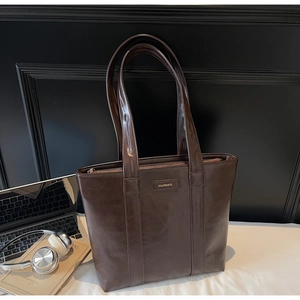 Gros plan du sac cabas en cuir marron foncé avec lettrage doré près d'un ordinateur