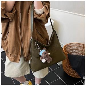 Detail of olive green tote bag with embossed pattern and bear charm pendant