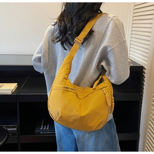 Detail showing a yellow crescent canvas bag with THREE TREES embroidery and cord zipper pull
