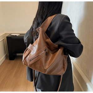 Detail of a brown leather Hobo bag featuring a metal zipper pocket and soft PU texture