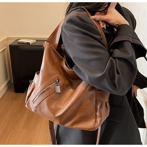 Detail view of large brown PU shoulder bag featuring side zipper and soft textured material