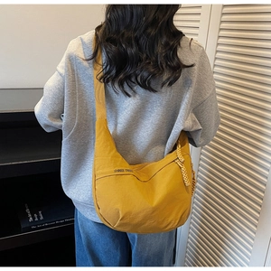 Detail of yellow canvas crescent crossbody bag showing adjustable wide strap and logo