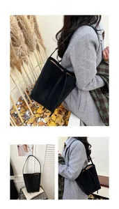 Detail view of a black suede bucket bag with drawstring strap in a cozy autumn setting