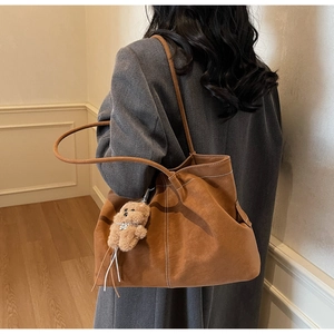Detail of vintage brown suede tote bag with white stitching and bear charm