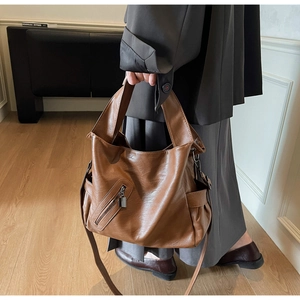 Detail of caramel oil wax leather tote bag with wide strap and side pockets on a model