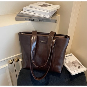 Vue détaillée du sac cabas en cuir marron foncé brillant avec logo et fines lanières