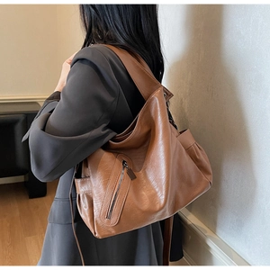 Detail of soft brown PU leather tote bag with stylish side zipper and slouchy drape texture