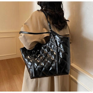 Vue détaillée du grand sac cabas noir matelassé porté avec un trench-coat beige classique