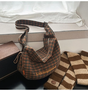 Detail of vintage plaid canvas hobo bag featuring yellow embroidery and zipper closure
