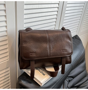Macro detail of dark brown flap crossbody bag with vintage wrinkled leather texture