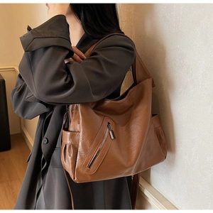 Detail view of large brown crossbody bag with retro leather texture and side pockets
