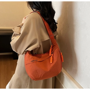 Detail of orange canvas crescent bag with black lettering and woven zipper pull