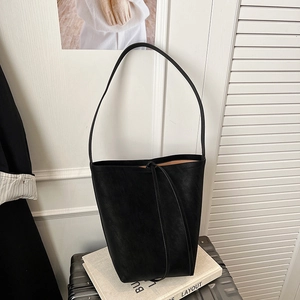 Detail view of black matte leather bucket bag with contrast brown lining on luggage