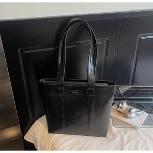 Détail du sac cabas en cuir noir brillant avec fermeture éclair argentée et fines bandoulières