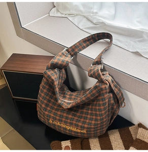Detail of vintage plaid canvas tote bag with yellow embroidery on a rustic table