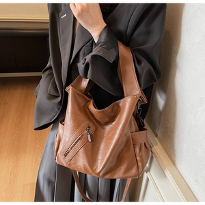 Detail of dark brown leather tote bag with pebble texture and front zipper pocket