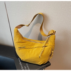Detail of yellow nylon crossbody bag featuring Three Trees logo and adjustable strap