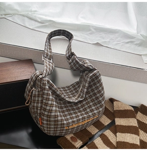 Detail view of the brown plaid canvas shoulder bag with orange letter embroidery