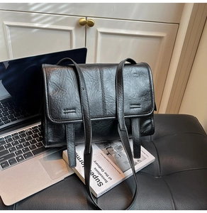 Detailed view of a black retro textured shoulder bag with laptop and lifestyle books