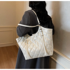 Close-up of white quilted tote bag with large diamond stitching and sleek shoulder straps