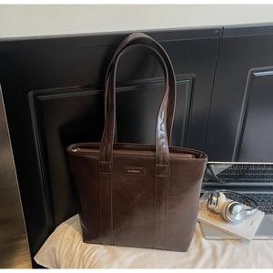 Détail du grand sac cabas marron foncé avec logo en relief sur cuir poli élégant